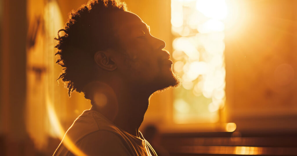 A man alone praying near a window in the morning growing in his faith