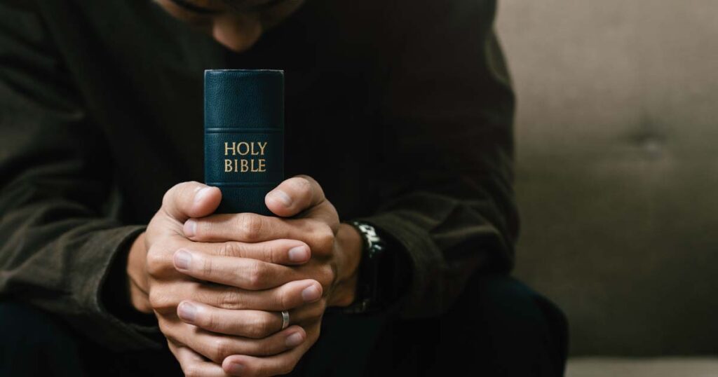 Man holding a Bible and saying a prayer to become a Christian