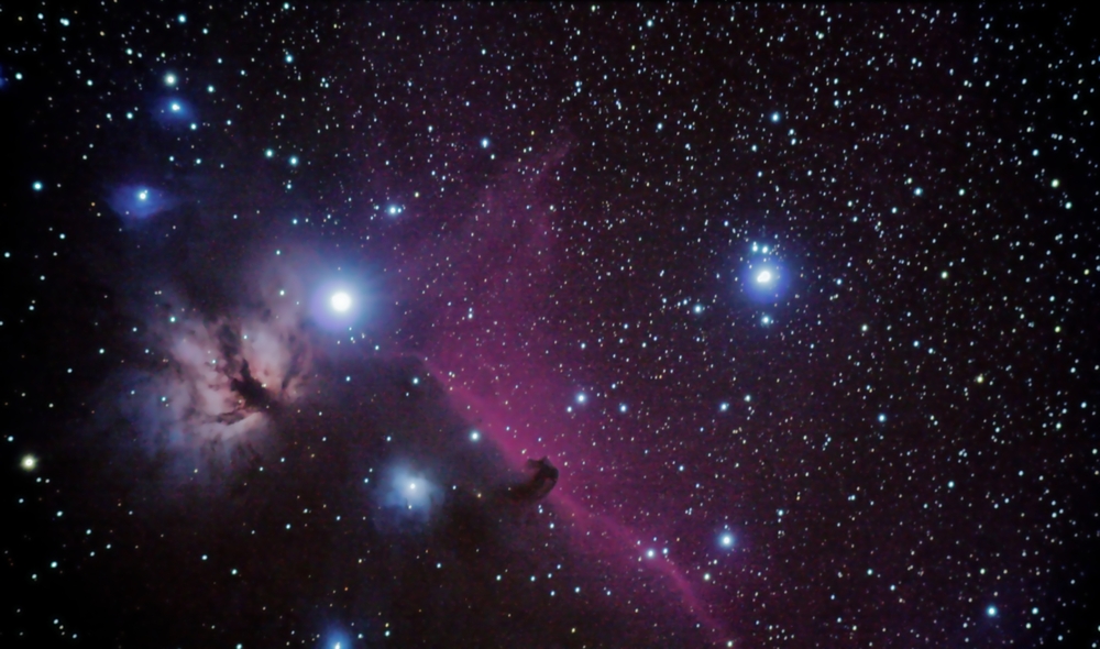 A starry sky with the Horsehead Nebula, a dark silhouette against a vibrant pink and purple background, surrounded by glowing stars.