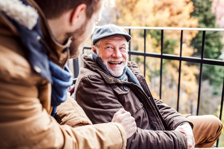 Two people sit together on an outdoor balcony in a thoughtful conversation, visually representing discussions with friends and family about evolution.