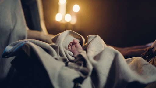 An infant's foot peeking out of swaddling blanket.