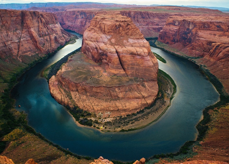A winding river curves sharply around a massive sandstone formation.