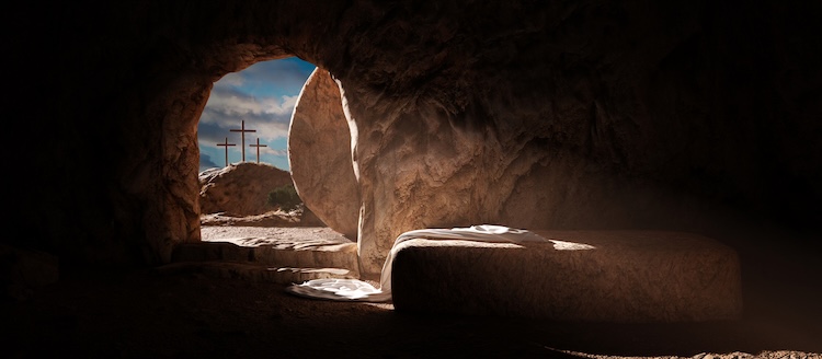 Sunlight streams into an empty tomb with a stone rolled aside. Three crosses stand on a distant hill under a blue sky.