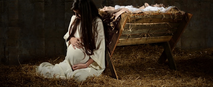 Pregnant Mary seated beside a simple wooden manger, reflecting on the coming birth of Jesus.
