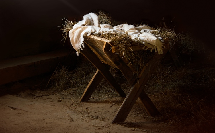 A simple wooden manger filled with straw in a quiet stable setting, illuminated by soft light, symbolizing prophecies of Jesus’ birth and the humble fulfillment of God’s promise.