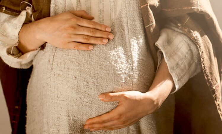 Softly lit image of Mary’s pregnant belly with her hands resting protectively over her womb, symbolizing prophecies of Jesus’ birth and the promise of the coming Messiah fulfilled.