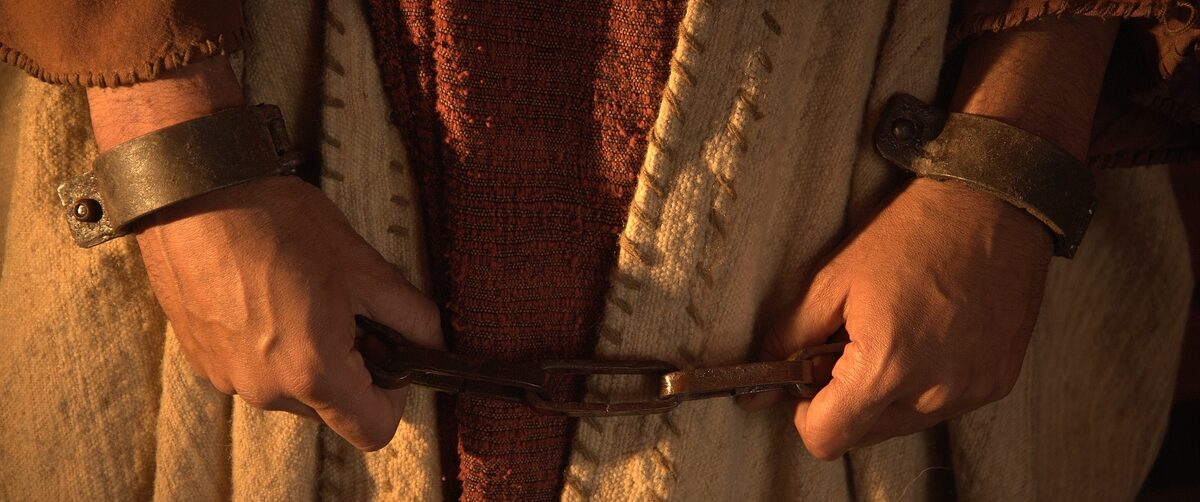 Close-up of Jesus’ hands bound in chains.