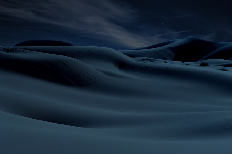 Dark, rolling sand dunes under a dim sky, symbolizing the realm of the dead.