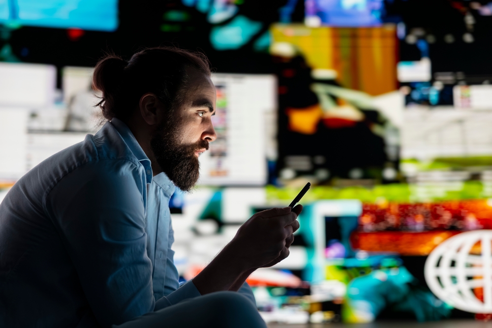 Man scrolling on his smartphone late at night, representing the mental and behavioral patterns of social media addiction.