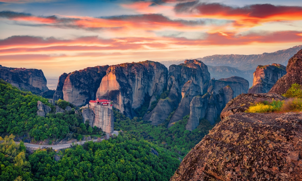 Far-off view of an Orthodox monastery atop a cliff in Kalabaka, Greece, at sunset.