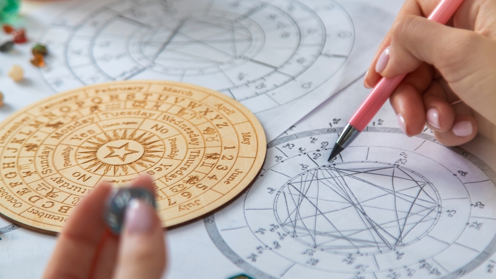 A person writing on an astrological chart, casting horoscopes.