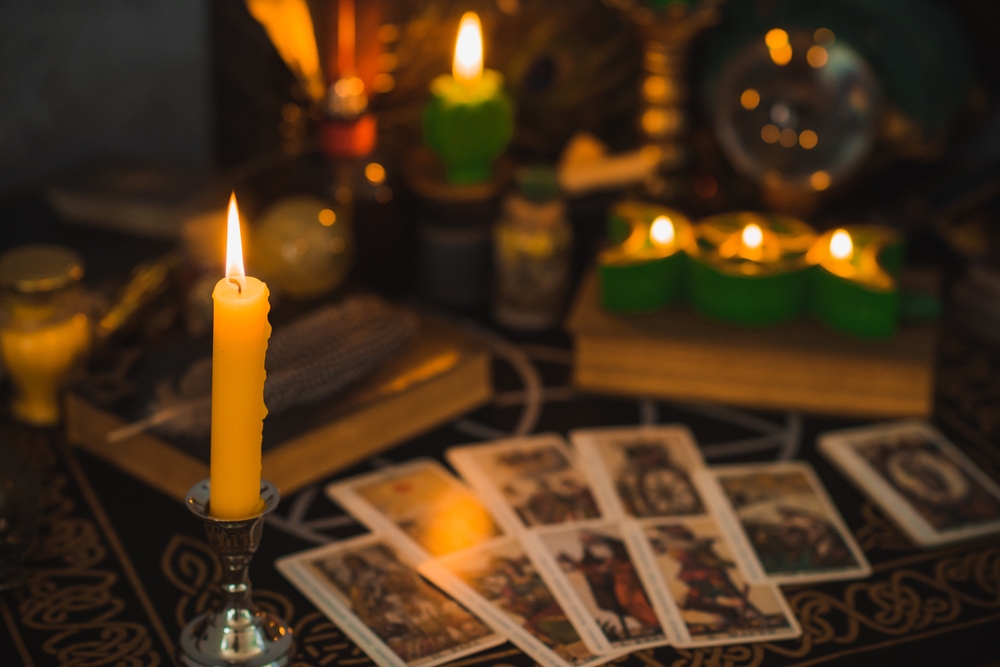 A candlelit table with tarot cards and other items used for occult practices that open doors to demonic activity.
