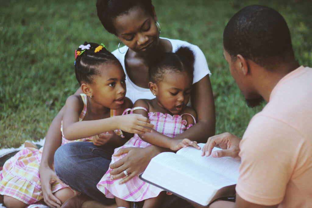 A mother reading with her children outdoors, illustrating the influence of women in Christianity through faith and family life.