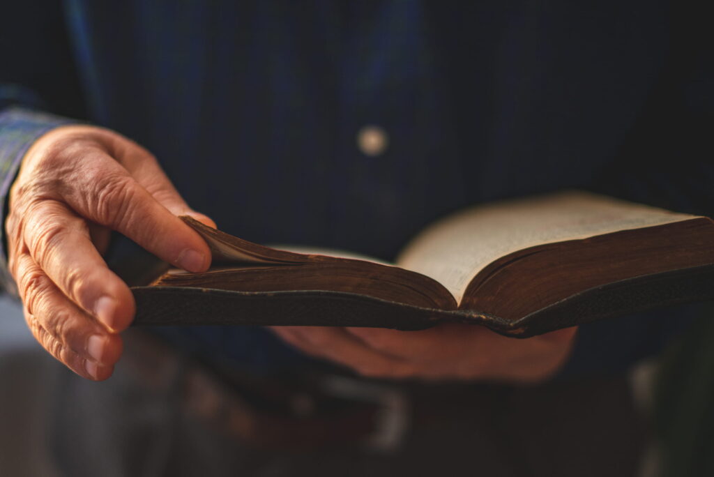 Person holding an open Bible while studying passages describing how long people lived in the Bible.
