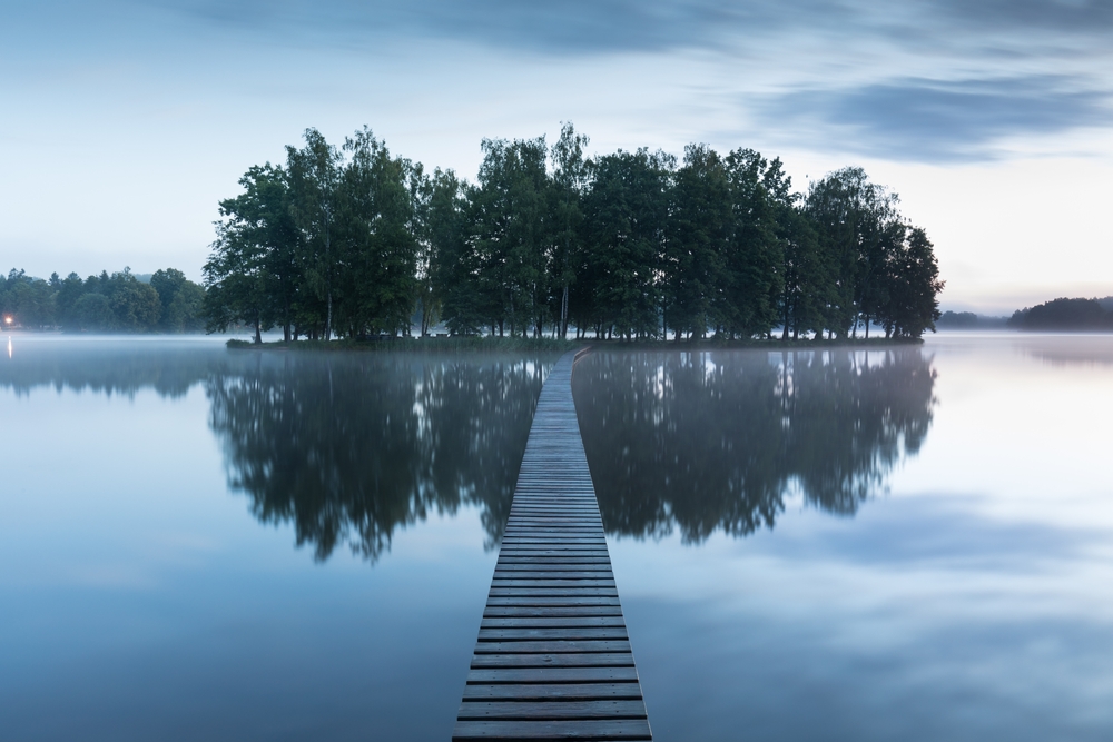 A wooden walkway to an island in the middle of a foggy lake