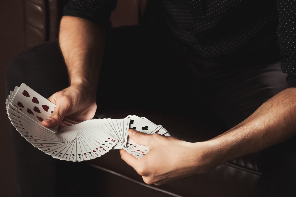 Magician performing a card trick with playing cards, illustrating the difference between magic and miracles.